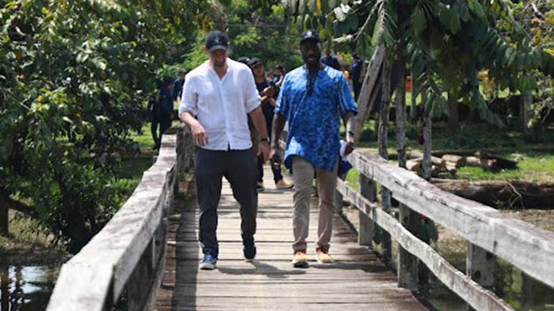 Tiamiyu in Brazil two men walking across wooden bridge over a river